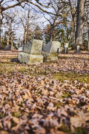 Fallen gravestones amidst autumn leaves in Lindenwood Cemetery, Indiana, capturing the serene melancholy of times passage.