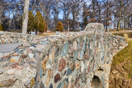 Timeless stone bridge amidst tranquil park in Fort Wayne, presenting a blend of history and natures beauty