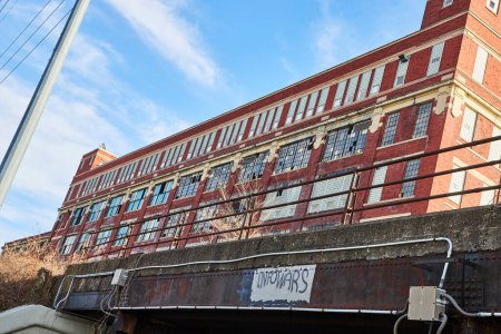 Edificio industrial abandonado y puente de graffiti bajo el cielo azul en Fort Wayne, Indiana - Un monumento a la fabricación del pasado
