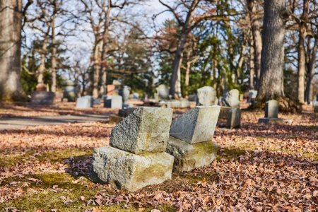 Fallen gravestones amidst autumn leaves, a poignant symbol of times passage in serene Lindenwood Cemetery, Indiana.