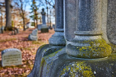 Automne au cimetière Lindenwood, Indiana. Ancien monument de granit altéré par le temps, niché parmi les feuilles tombées.