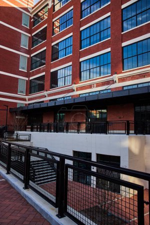 Téléchargez les photos : Electric Works chef-d'œuvre architectural moderne à Fort Wayne, Indiana, mettant en valeur un mélange d'ancien et de nouveau avec des briques rouges et des fenêtres en verre réfléchissant contre un ciel clair. - en image libre de droit