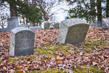 Düstere Herbstszene auf dem historischen Lindenwood-Friedhof in Fort Wayne, Indiana, mit gealterten Grabsteinen und umgefallenen Blättern