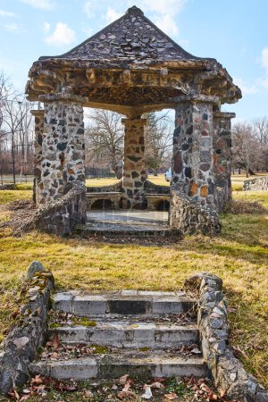 Téléchargez les photos : Gazebo rustique en pierre baigné de lumière du jour au cimetière Lindenwood, Fort Wayne, Indiana, un symbole de tranquillité et de beauté intemporelle. - en image libre de droit