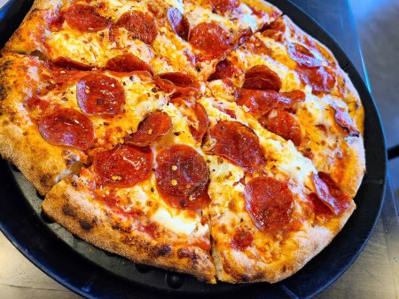 Pizza de pepperoni clásica recién horneada, servida caliente en una bandeja de cocina en Garrett, Indiana, simbolizando comodidad e indulgencia.