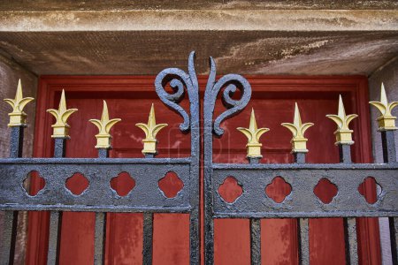 Elegant Wrought Iron Fence with Gold Fleur-de-lis Finials Against a Red Door at Lindenwood Cemetery, Fort Wayne