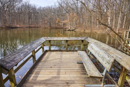 Tranquil autumn scene at Lindenwood Preserve, Indiana, featuring a rustic dock extending over a serene lake surrounded by a dormant forest.