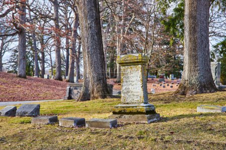 Foto de Tarde de otoño en el cementerio de Lindenwood, Fort Wayne, Indiana - La lápida resistida en medio de hojas caídas evoca reflexión y paso del tiempo. - Imagen libre de derechos