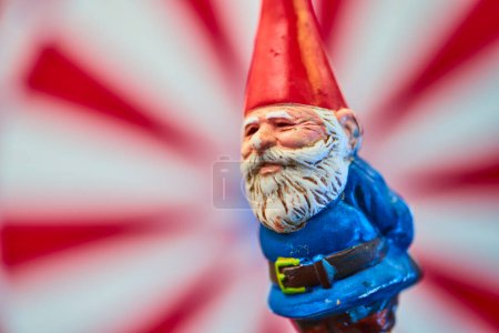 Whimsical garden gnome in vibrant attire, caught in a playful macro shot in Fort Wayne, Indiana, against a dynamic red and white swirl.