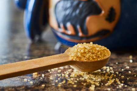 Close-up of golden brown sugar crystals on a wooden spoon, in a rustic kitchen setting in Fort Wayne, Indiana - perfect for baking and natural foods