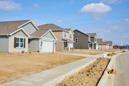 Modern, newly built single-family homes line a street in a developing suburban neighborhood in Fort Wayne, Indiana, symbolizing the American Dream.