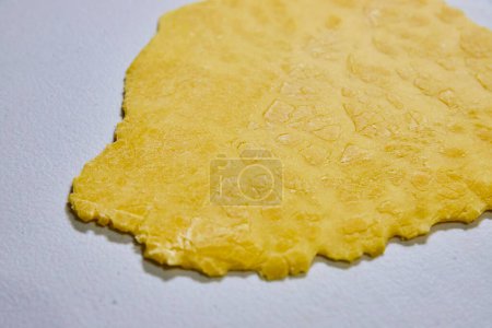 Foto de Masa de pasta amarilla laminada a mano sobre una superficie blanca, mostrando el proceso rústico de hacer pasta casera en Fort Wayne, Indiana. - Imagen libre de derechos