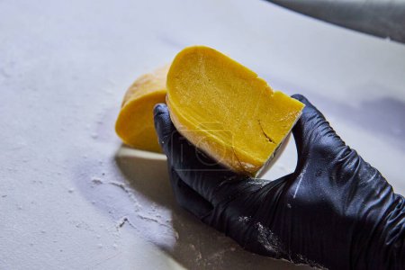 Geschickte Hände in schwarzen Handschuhen formen leuchtend gelben hausgemachten Nudelteig auf einer sauberen Küchenarbeitsplatte in Fort Wayne, Indiana