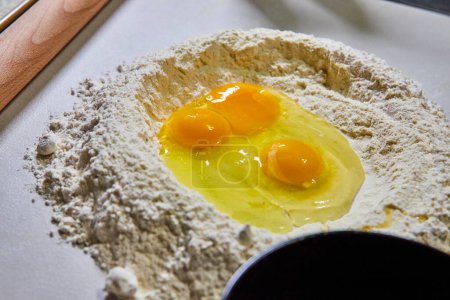Fresh start to homemade pasta with raw eggs nestled in a mound of flour, a classic cooking scene in a Fort Wayne, Indiana kitchen