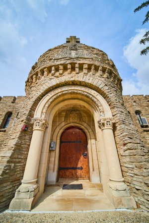Grandiosidad gótica de la entrada del Bishop Simon Brute College, mostrando arquitectura histórica y herencia cristiana bajo un cielo primaveral.
