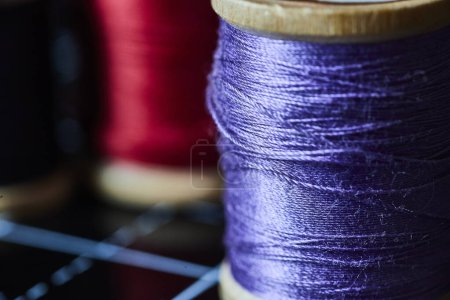 Close-up of vibrant purple and red thread spools, highlighting texture and craftsmanship, perfect for textile and fashion design