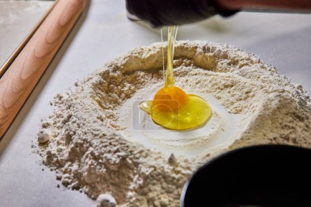 Close-up of raw egg nestled in flour mound, signaling the start of homemade pasta preparation in a sunny, Fort Wayne kitchen.