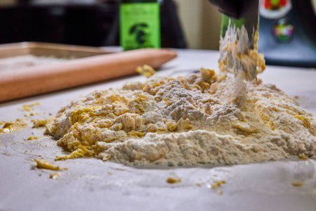 Hands-on crafting of homemade pasta in a cozy Fort Wayne kitchen, with a dusting of flour over fresh ingredients.