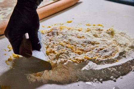 Preparación artesanal de pasta en la cocina de Fort Wayne - Chef calificado incorpora huevos frescos en el molino de harina con cortador de masa
