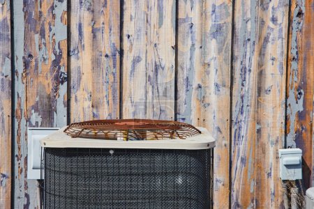 Rustic meets modern with a weathered air conditioning unit against a peeling barnwood wall in Spiceland, Indiana.