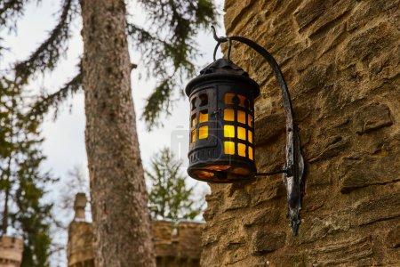 Téléchargez les photos : Lanterne vintage sur un mur de pierre à Bishop Simon Brute College, Indiana, projetant une lueur chaude dans un cadre calme et rustique - en image libre de droit