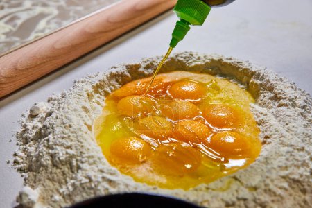Téléchargez les photos : Ingrédients frais dans un puits de farine pour pâtes maison, avec un filet d'huile d'olive, dans une cuisine de Fort Wayne - en image libre de droit