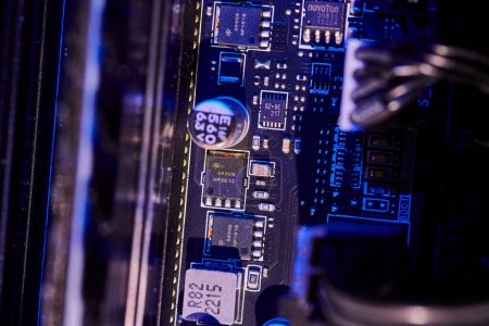 Close-up view of a high-tech computer motherboard bathed in cool blue light showcasing intricate electronic components. Macro image from Indiana, USA.
