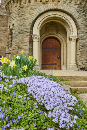 Printemps à Bishop Simon Brute College, Indiana - une floraison vibrante de pervenches et de jonquilles ornant l'architecture historique en pierre.