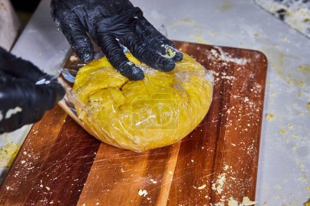 Téléchargez les photos : Fabrication de pâtes artisanales à Fort Wayne, Indiana - Mains gantées préparant habilement de la pâte jaune fraîche - en image libre de droit