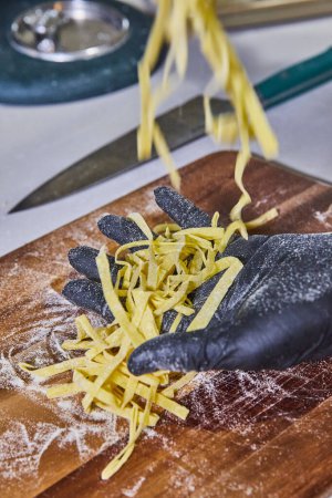 Artisanal Pasta Preparation in Indiana - Hands delicately hold fresh tagliolini over a flour-dusted board, capturing the essence of homemade gourmet cooking.