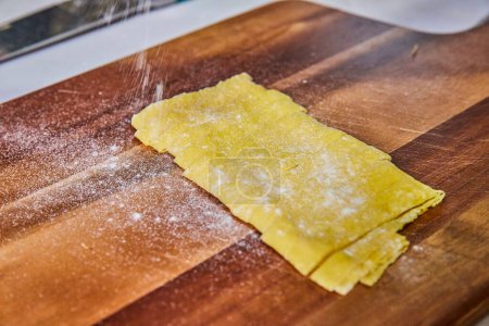 Handmade fettuccine pasta dough on a rustic cutting board, capturing the art of Italian cooking in Fort Wayne, Indiana.