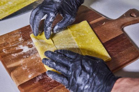Artisan hands skillfully crafting homemade Pappardelle pasta in a rustic kitchen setting in Fort Wayne, Indiana. A testament to culinary mastery and tradition.