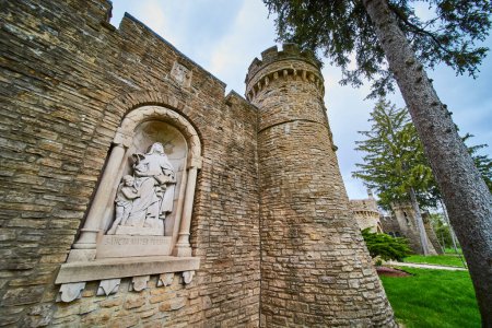 Springtime at Bishop Simon Brute College, Indianapolis - St. Teresa sculpture in medieval-style tower, a testament to Christian heritage.