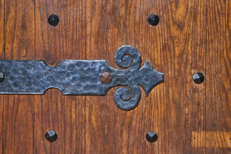 Charnière en fer forgé artisanal sur une porte en bois antique au Collège Bishop Simon Brute, symbolisant l'artisanat intemporel.