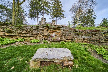 Serene Spring morning at Bishop Simon Brute College, featuring a rustic stone wall with floral alcove in a tranquil garden setting