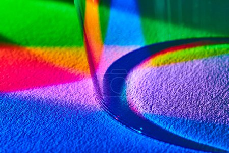 Macro disparo de luz refractando a través de una copa de vino, lanzando un espectro de arco iris vívido en una superficie texturizada en Fort Wayne, Indiana.