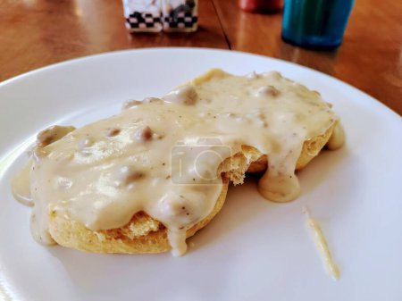 Hearty biscuits and gravy on a white plate, embodying a comforting Southern breakfast in a cozy setting.