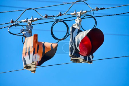 Vivid urban traffic lights with camouflage patterns regulate flow under a clear blue sky in Fort Wayne.