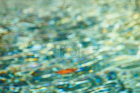 Abstract blur of light on water in Fort Wayne, evoking tranquility with vibrant blue and gold hues.