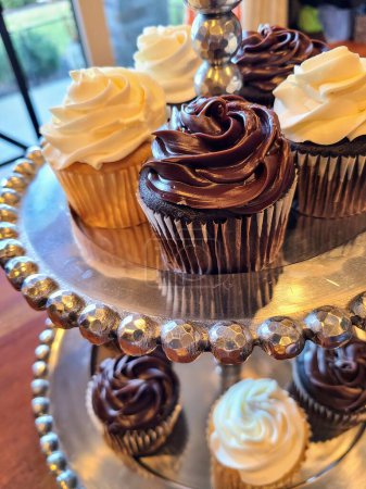 Elegantes cupcakes en un soporte metálico, exhibidos en un acogedor entorno de panadería Fort Wayne. Perfecto para promociones de arte culinario.