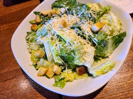 Frischer Caesar-Salat in einer weißen Schüssel auf einem Holztisch, Inbegriff für Gourmet-Essen in Fort Wayne, Indiana.