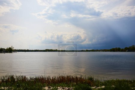 Lago Sereno Winona bajo cielos tormentosos, capturando naturalezas, tranquilidad y drama en Varsovia, Indiana.