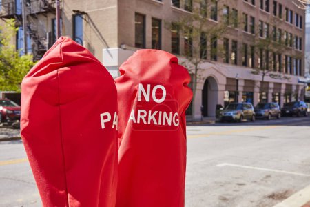 Téléchargez les photos : Vibrant rouge AUCUN PARKING couvre-compteur sur une rue ensoleillée du centre-ville de Fort Wayne, mettant en valeur la vie urbaine et la réglementation. - en image libre de droit
