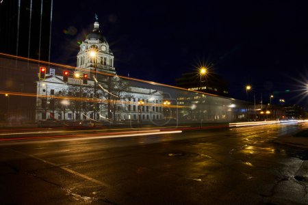 Téléchargez les photos : Le palais de justice historique de Fort Waynes brille la nuit, contrastant avec les lumières modernes de la ville et les lignes de circulation animées. - en image libre de droit