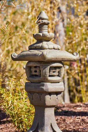 Foto de Linterna de piedra tradicional de Asia Oriental en un entorno de jardín sereno en Fort Wayne, Indiana, haciendo hincapié en la tranquilidad y la cultura. - Imagen libre de derechos