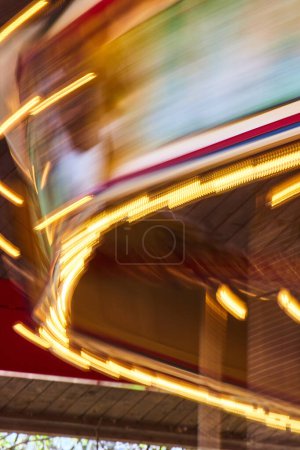 Téléchargez les photos : Les lumières vibrantes du carrousel s'estompent en stries de couleur, capturant l'esprit festif de la scène nocturne de Fort Waynes. - en image libre de droit