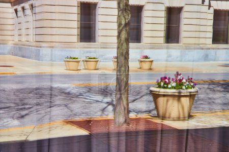 Téléchargez les photos : Scène urbaine animée avec des pots de fleurs colorés et un majestueux bâtiment en pierre au centre-ville de Fort Wayne. - en image libre de droit