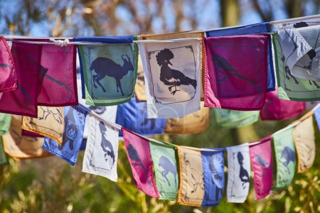 Colorful prayer flags with wildlife silhouettes flutter in a serene, natural setting at Fort Wayne, Indiana.