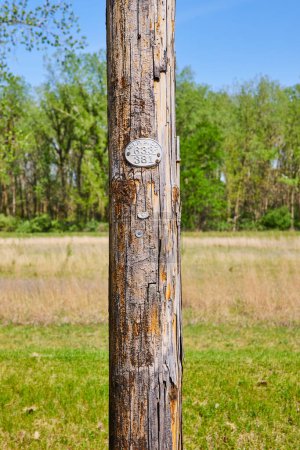 Poteau utilitaire vieillissant marqué W.P. S.CO 633 381 se dresse dans un contexte de paysage rural de l'Indiana.