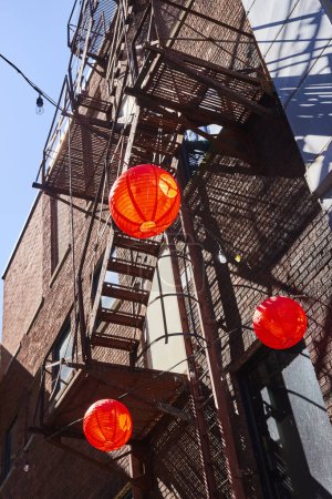 Vibrant red lanterns contrast a rustic urban backdrop in downtown Fort Wayne, capturing a festive city vibe.